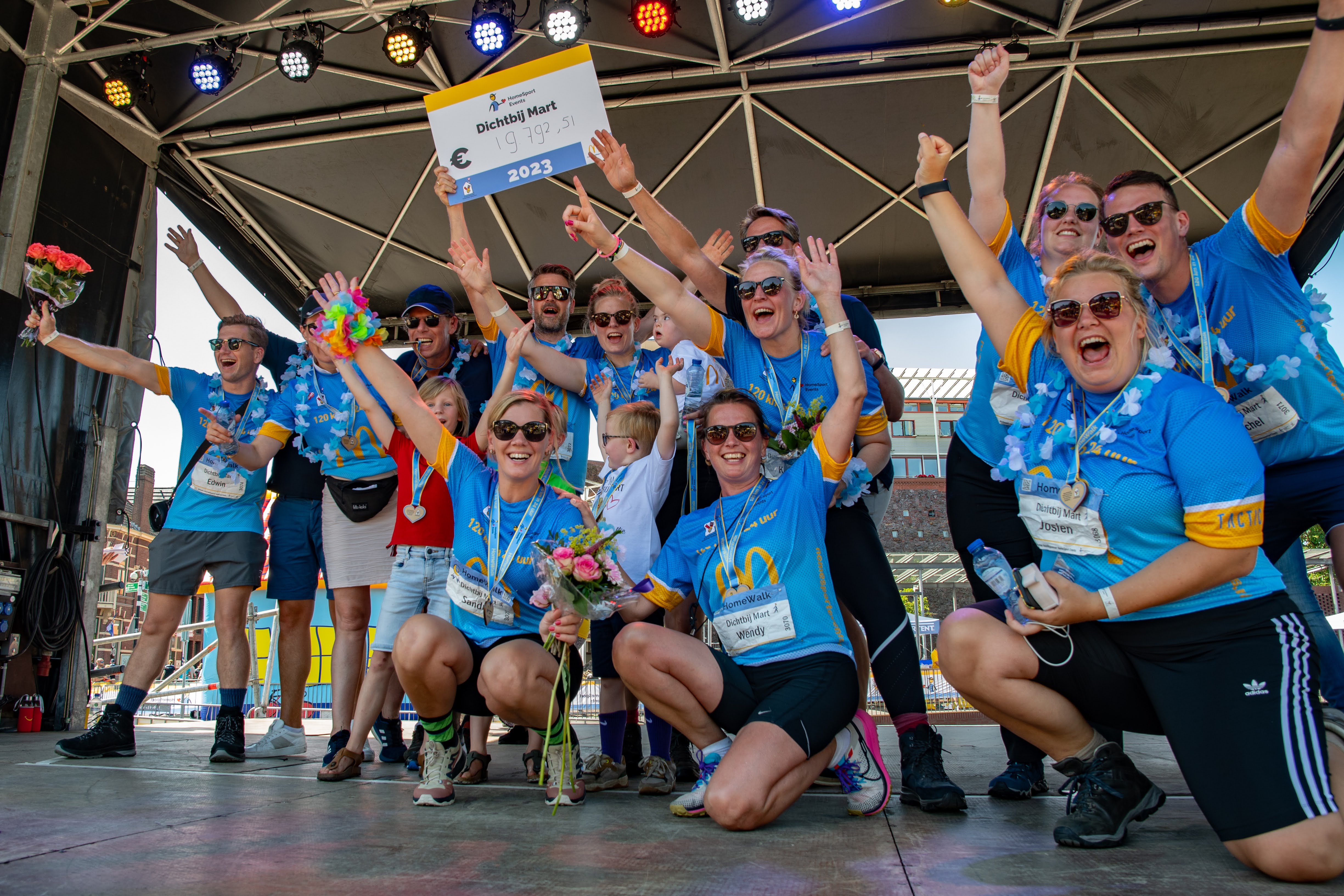 HomeSport Events team bij de finish met cheque op het podium