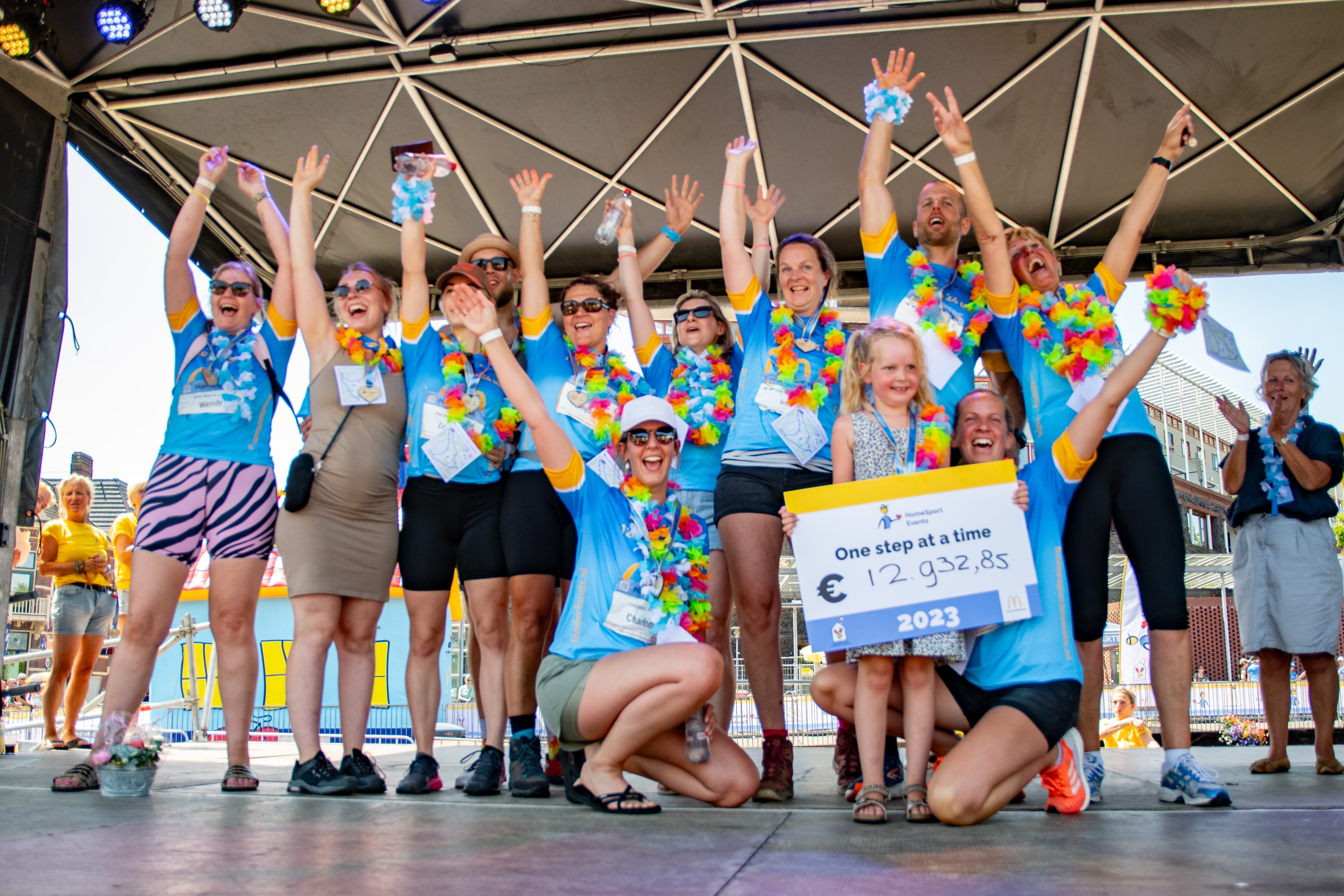 HomeSport Events team bij de finish met cheque op het podium